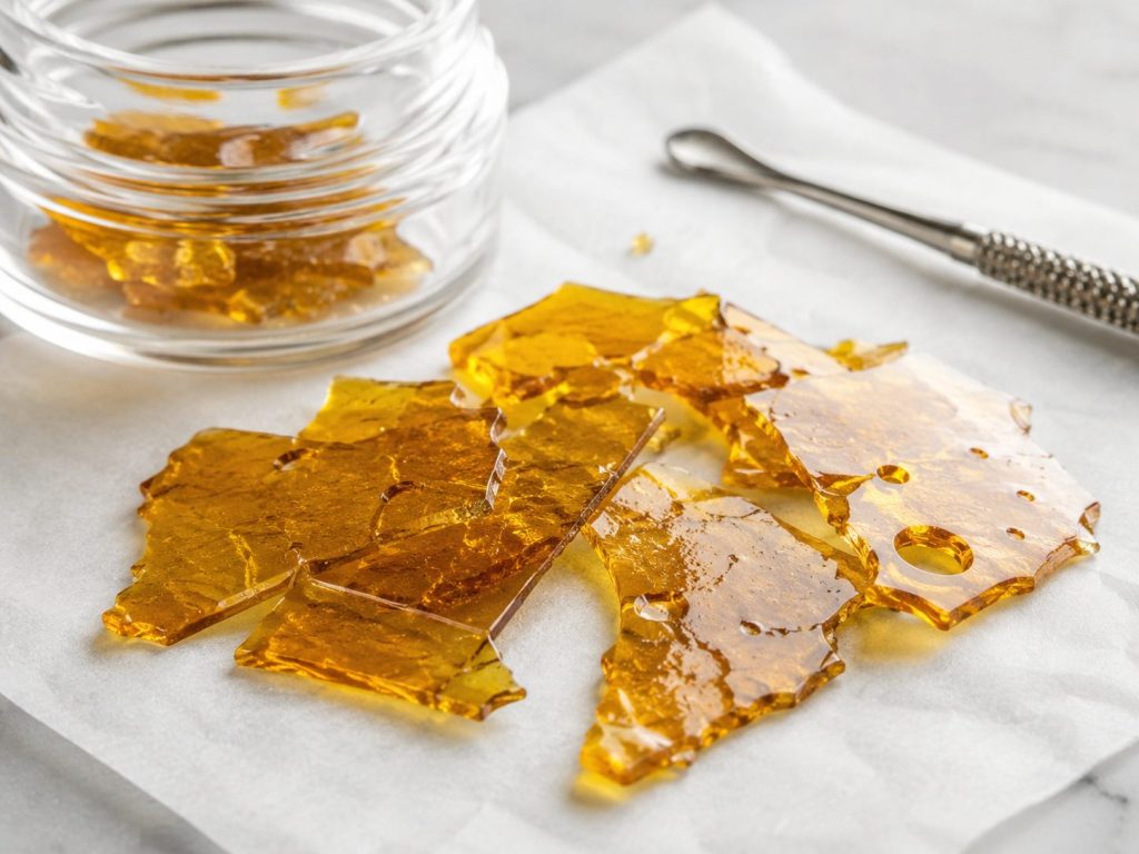 Golden cannabis shatter concentrate with glass like texture on parchment paper